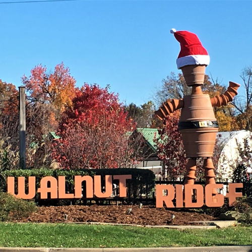 The Walnut Ridge sign on display outside on a clear day next to a large statue with a holiday hat on.