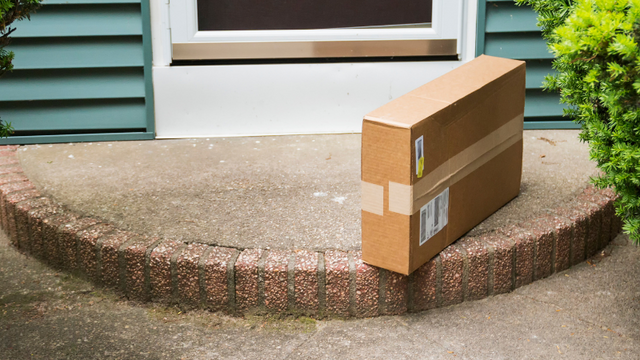 A cardboard box delivered to a houses front door step. 